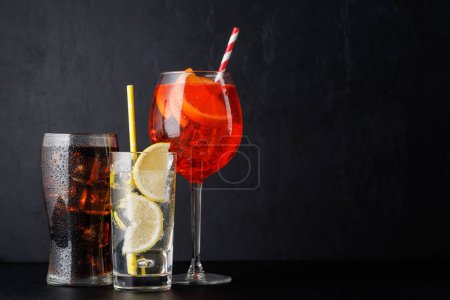 Aperol spritz, cola and gin tonic cocktails on black with copy space