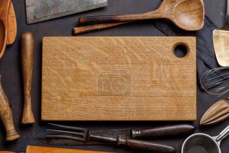 Foto de Esenciales culinarios: Diversos utensilios de cocina y tabla de madera sobre mesa de piedra. Puesta plana - Imagen libre de derechos