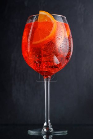 Aperol spritz cocktail with orange slice and ice on dark background