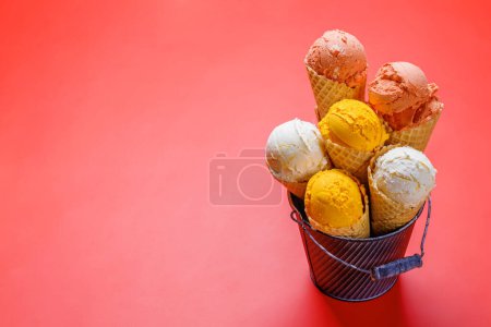 Foto de Surtido de sabores de helado en deliciosos conos de gofres, un regalo para todos los papilas gustativas. Sobre fondo rojo con espacio de copia - Imagen libre de derechos