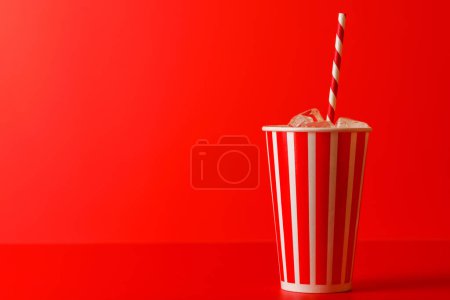 Pappbecher mit Cola und Eis auf rotem Hintergrund, mit Kopierraum
