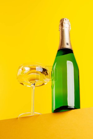 Champagne elegance: Glass and bottle against a vibrant yellow background. With copy space