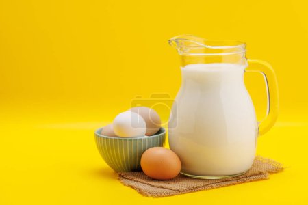 Foto de Jarra de leche con huevos sobre fondo amarillo con espacio para copiar - Imagen libre de derechos