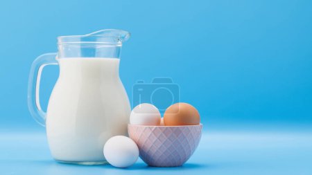 Téléchargez les photos : Pichet de lait aux œufs sur fond bleu avec espace de copie - en image libre de droit
