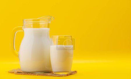 Frische Milch in Krug und Glas auf gelbem Hintergrund mit Kopierraum