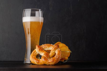 Cerveza, patatas fritas y pretzel. Sobre fondo oscuro con espacio de copia