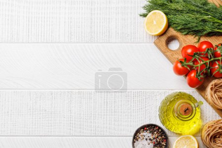 Photo for Cooking scene: Cherry tomatoes, pasta, spices on table. Flat lay with copy space - Royalty Free Image