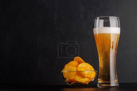 Foto de Cerveza y patatas fritas. Sobre fondo oscuro con espacio de copia - Imagen libre de derechos