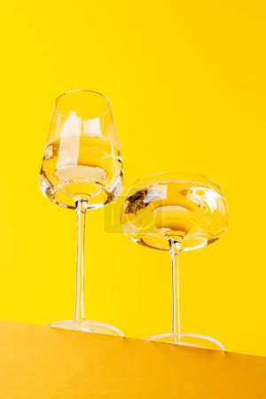 Champagne elegance: Glasses with sparkling wine against a vibrant yellow background. With copy space