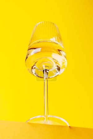Champagne elegance: Glass with sparkling wine against a vibrant yellow background. With copy space