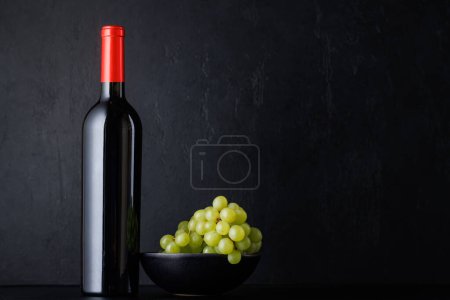 Téléchargez les photos : Bouteille de vin rouge sur noir avec espace de copie - en image libre de droit