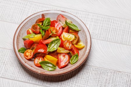 Photo for Tomato salad with fresh basil leaves and olive oil. With copy space - Royalty Free Image