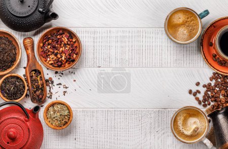 Téléchargez les photos : Affichage alléchant de grains de café torréfiés et de diverses feuilles de thé sèches, accompagnés d'une tasse à café expresso et d'une théière. Pose plate avec espace de copie - en image libre de droit