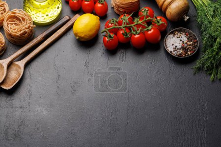 Téléchargez les photos : Scène de cuisson : tomates cerises, pâtes, épices sur la table. Pose plate avec espace de copie - en image libre de droit