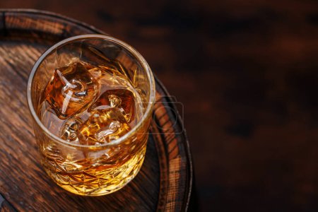 Verre à whisky avec glace sur un tonneau rustique, une gorgée classique. Avec espace de copie