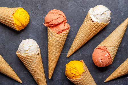 Photo for Assorted ice cream flavours in delightful waffle cones, a treat for every taste bud. Over stone background. Flat lay - Royalty Free Image