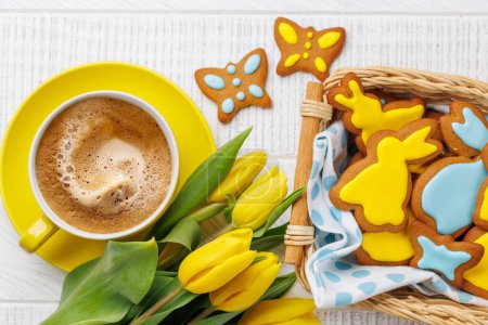 Téléchargez les photos : Scène de Pâques avec des biscuits au pain d'épice en forme de lapin, des tulipes jaunes et une tasse de café. Pose plate - en image libre de droit