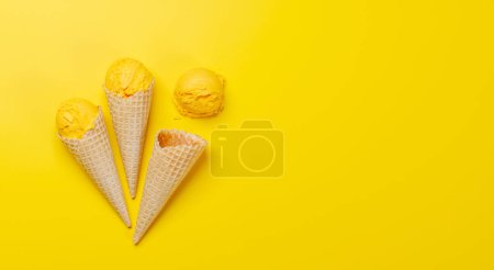 Téléchargez les photos : Glace au citron dans de délicieux cônes de gaufres, un régal pour tous les papilles. Sur fond jaune avec espace de copie, pose plate - en image libre de droit