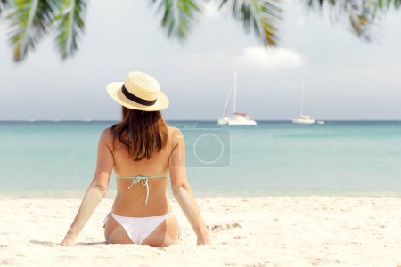 Téléchargez les photos : Woman sitting on the sea beach enjoying and relaxing in summer - en image libre de droit