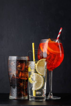 Téléchargez les photos : Aperol spritz, cola et gin tonic cocktails sur noir avec espace de copie - en image libre de droit