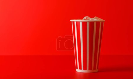 Foto de Taza de papel con cola y hielo sobre fondo rojo, con espacio para copiar - Imagen libre de derechos