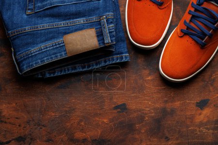 Foto de Ropa de hombre sobre fondo de madera: Jeans, Sneakers, Gafas graduadas, Lay plana con espacio de copia - Imagen libre de derechos