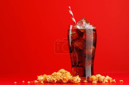 Cola mit Eis und Popcorn auf rotem Hintergrund, mit Kopierraum