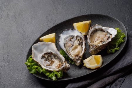Fresh oysters with lemon on plate. Flat lay