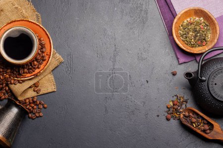 A tantalizing display of roasted coffee beans and dry tea leaves, accompanied by an espresso coffee cup and a teapot. Flat lay with copy space