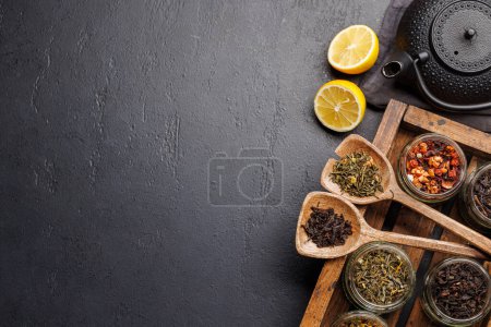 Surtido de la hora del té: Varias hojas de té seco y tetera. Piso con espacio de copia
