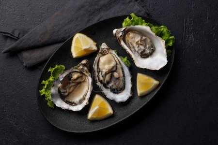 Fresh oysters with lemon on plate. Flat lay