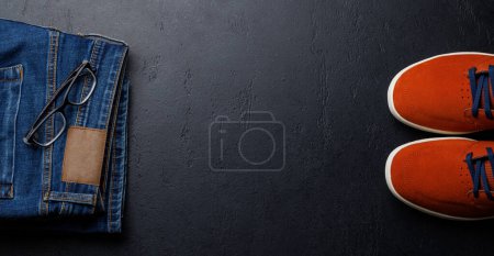 Photo for Men's Clothing on stone Background: Jeans, Sneakers, Eyeglasses, Flat Lay with Copy Space - Royalty Free Image