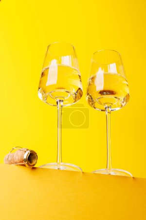 Champagne elegance: Glasses with sparkling wine against a vibrant yellow background. With copy space