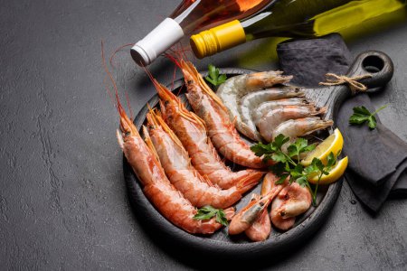 A top view of fresh seafood such as shrimp, langoustines, and trout steaks, accompanied by white and rose wine. With copy space