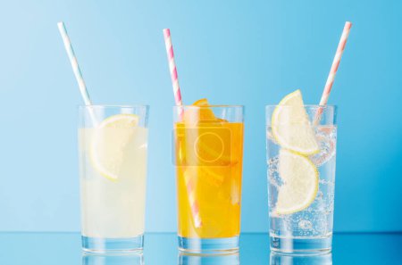 Diverses limonades avec glace dans des verres sur fond bleu