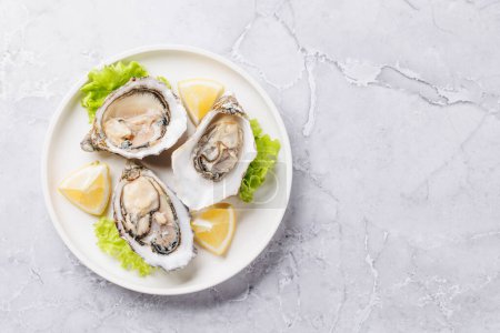 Fresh oysters with lemon on plate. Flat lay with copy space