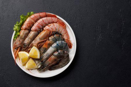 Téléchargez les photos : Crevettes crues sur assiette, prêtes à cuire. Pose plate avec espace de copie - en image libre de droit