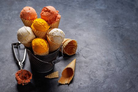 Foto de Surtido de sabores de helado en deliciosos conos de gofres, un regalo para todos los papilas gustativas. Sobre fondo de piedra con espacio de copia - Imagen libre de derechos