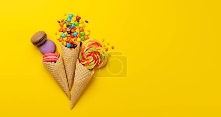 Photo for Various colorful candies, lollipops, and macaroons. Flat lay sweets over yellow background with copy space - Royalty Free Image