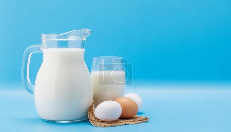 Téléchargez les photos : Pichet de lait aux œufs sur fond bleu avec espace de copie - en image libre de droit