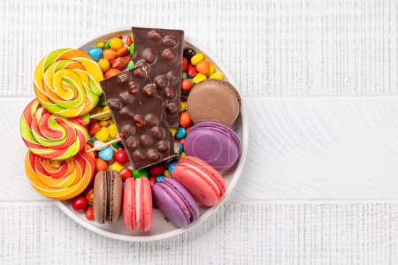 Photo for Various colorful candies, lollipops, and macaroons. Flat lay over wooden background with copy space - Royalty Free Image