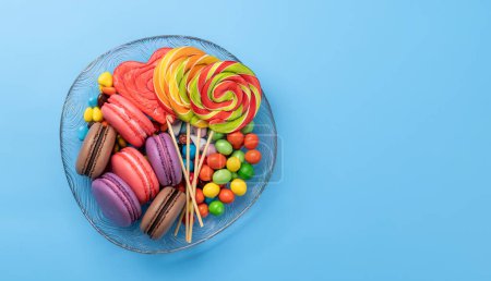 Photo for Various colorful candies, lollipops, and macaroons. Flat lay sweets over blue background with copy space - Royalty Free Image