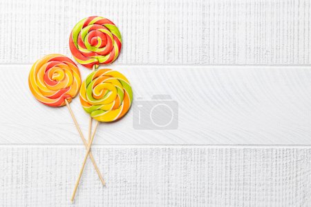 Foto de Varios caramelos de colores, piruletas. Dulces planos sobre fondo de madera con espacio para copiar - Imagen libre de derechos