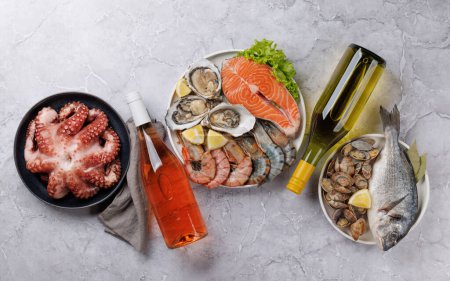 Foto de Delicia de plato de mariscos: camarones, salmón, ostras en abundancia. Piso con botellas de vino - Imagen libre de derechos