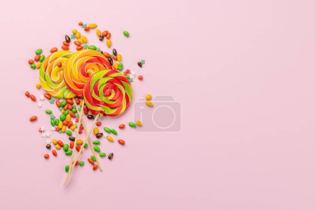 Foto de Varios caramelos de colores, piruletas. Dulces planos sobre fondo rosa con espacio para copiar - Imagen libre de derechos
