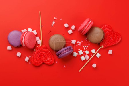 Photo for Various colorful candies, lollipops, and macaroons. Flat lay over red background - Royalty Free Image