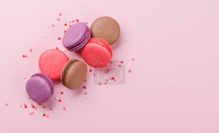 Téléchargez les photos : Divers macarons colorés. Bonbons amour sur fond rose avec espace de copie - en image libre de droit