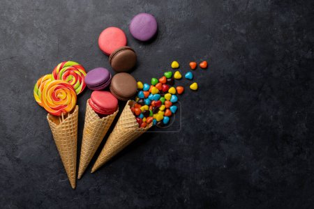 Photo for Various colorful candies, lollipops, and macaroons. Flat lay sweets over stone background with copy space - Royalty Free Image