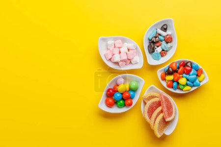 Foto de Varios caramelos de colores, piruletas. Piso sobre fondo amarillo con espacio de copia - Imagen libre de derechos