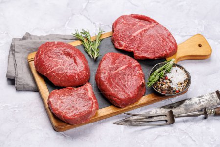 Photo for Raw beef fillet steaks on a cutting board, fresh and uncooked. Closeup - Royalty Free Image
